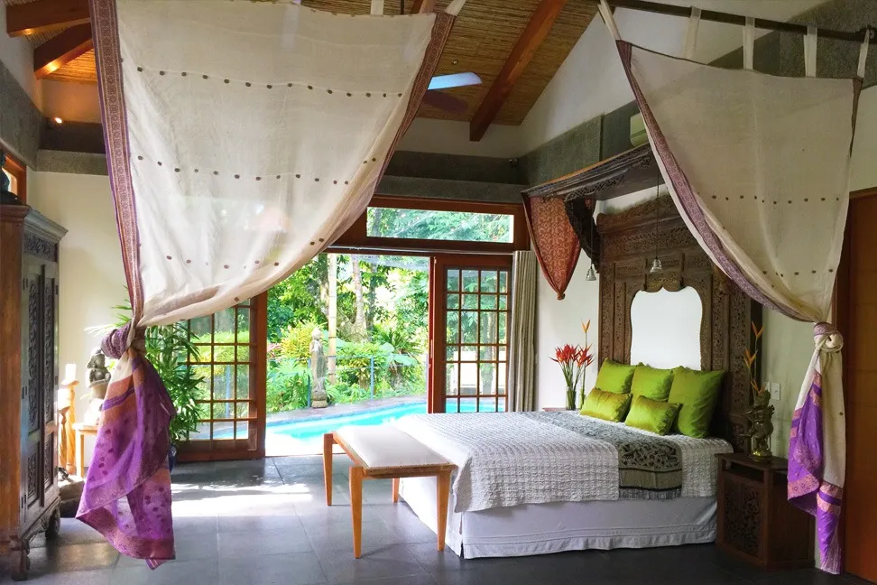 Private villa bedroom with king bed opening onto the pool deck